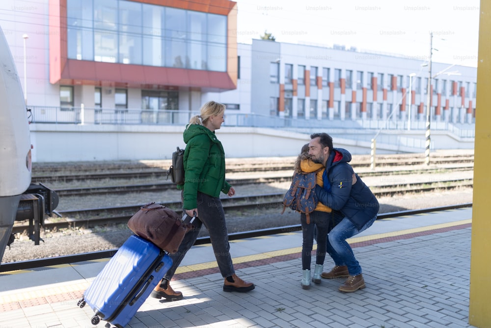 An Ukrainian refugee family hugging at railway station together, reunion after war.