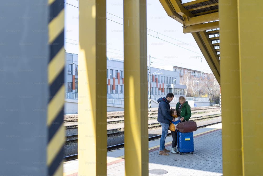 An Ukrainian refugee family with luggage at railway station together, Ukrainian war concept.