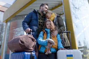 An Ukrainian refugee family with luggage at railway station together, Ukrainian war concept.