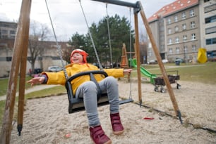 Kleines Mädchen mit Down-Syndrom auf Schaukel im Freien in Playgraound.