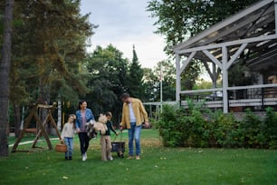 Una familia joven y feliz con canasta y manta que va a hacer un picnic al aire libre en el área del restaurante.