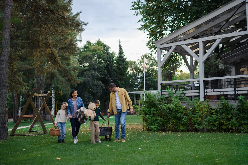 Eine glückliche junge Familie mit Korb und Decke, die im Freien im Restaurantbereich picknicken wird.