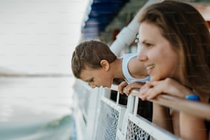 Um garotinho curioso com a mãe olhando para fora do barco a motor.