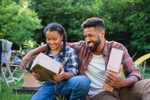 A happy young man with small sister spending time outdoors in backyard, laughing.