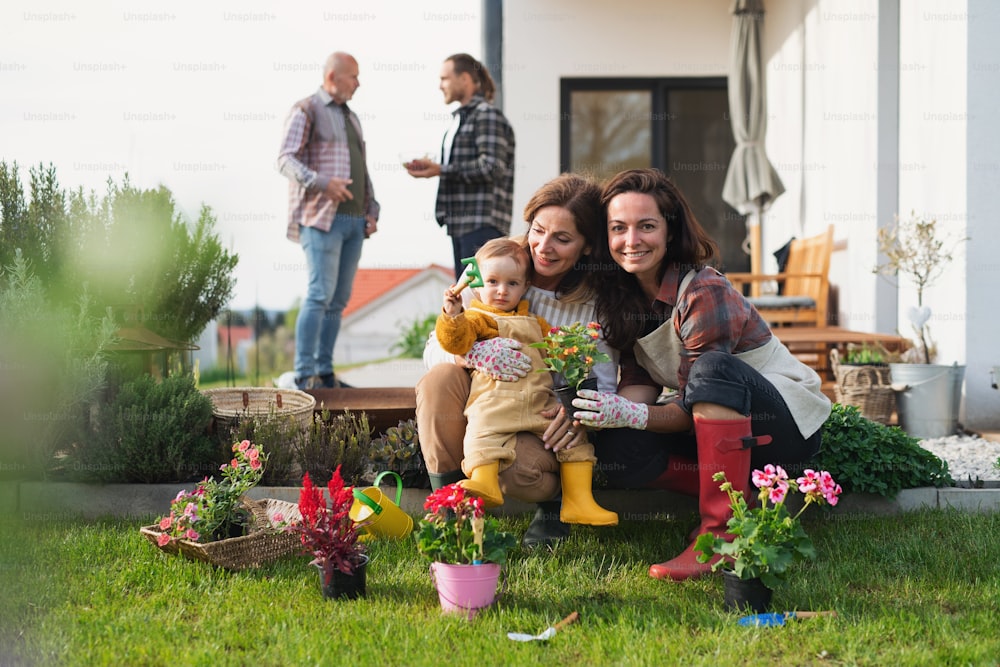 Eine glückliche Mehrgenerationenfamilie im Freien, die Blumen im Garten zu Hause pflanzt, Gartenkonzept.