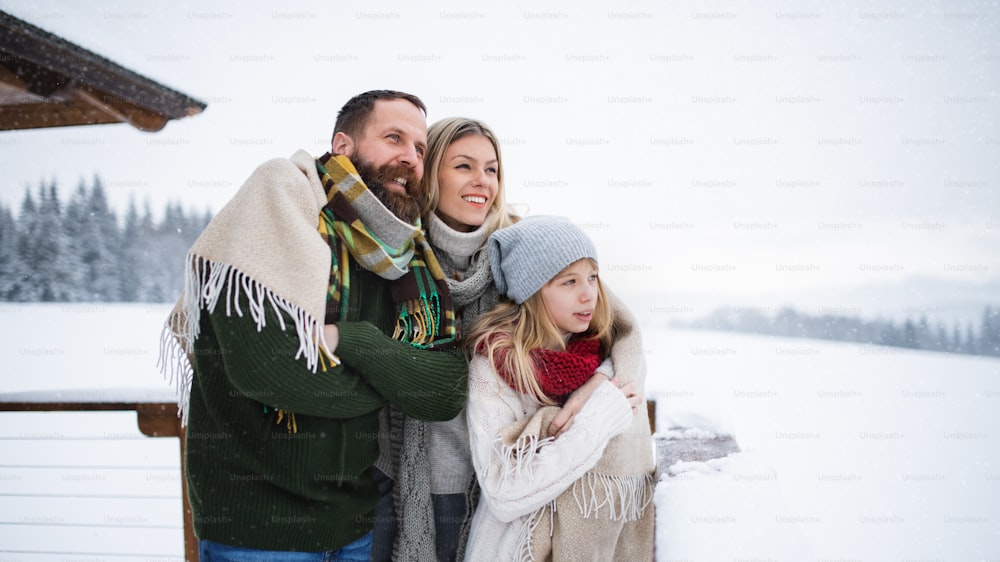 Glückliche Familie mit kleiner Tochter auf Terrasse im Freien, Urlaub in der Winternatur.