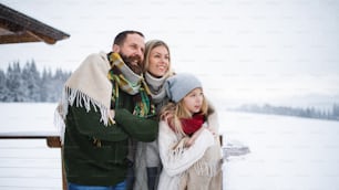 Familia feliz con hija pequeña en terraza al aire libre, vacaciones en invierno naturaleza.