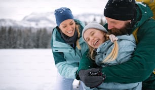 Happy family with small daughter hugging outdoors in winter nature