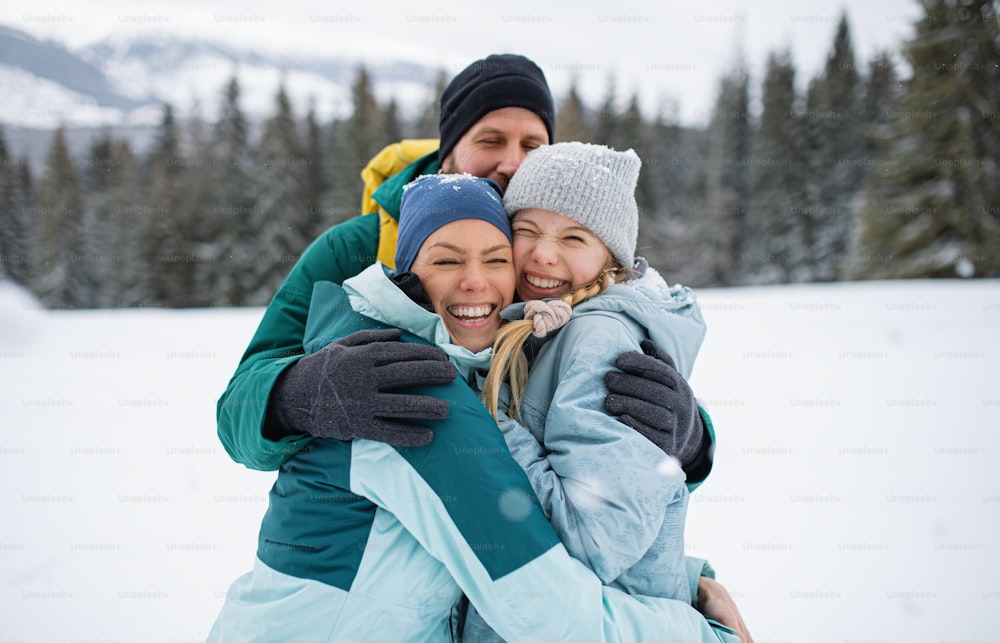 Happy family with small daughter hugging outdoors in winter nature, Tatra mountains in Slovakia.