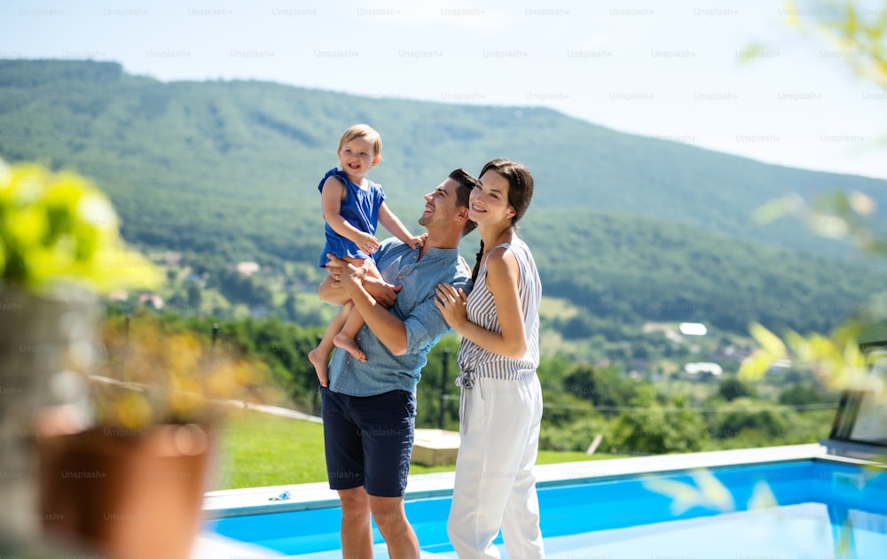 Retrato da família jovem com a filha pequena ao ar livre no jardim do quintal, relaxante.