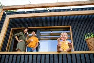 Low-angle view of young family with small daughter outdoors, weekend away in container house in countryside.
