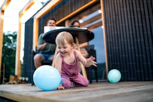 Young family with small daughter blowing bubbles outdoors, weekend away in container house in countryside.