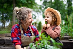 Happy mother with small daughter gardening on farm, growing organic vegetables.