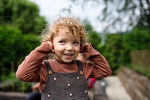 Porträt eines niedlichen kleinen Mädchens, das auf dem Bauernhof steht und Kirschohrringe hält.