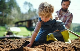 정원에서 야외에서 일하는 작은 아들을 둔 성숙한 아버지, 지속 가능한 라이프스타일 개념.
