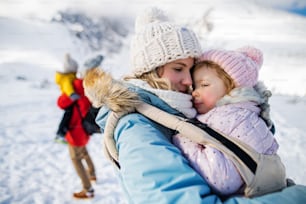 Portrait de mère avec une petite fille heureuse en porteur debout dans la nature hivernale, se reposant.