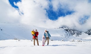 Vista frontale ritratto di padre e madre con figlio piccolo nella natura invernale, in piedi nella neve.