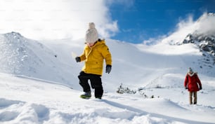 Father with happy small son walking in snow in winter nature, holiday concept.