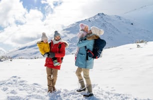Retrato frontal de padre y madre con dos niños pequeños en la naturaleza invernal, de pie en la nieve.
