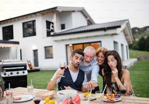 Portrait of people outdoors on family garden barbecue, taking selfie with smartphone.