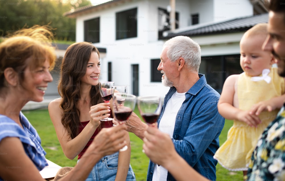 Retrato de personas con vino al aire libre en la barbacoa del jardín familiar, bebiendo vino.