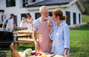 Portrait d’une famille multigénérationnelle en plein air sur barbecue de jardin, grillades et conversation.