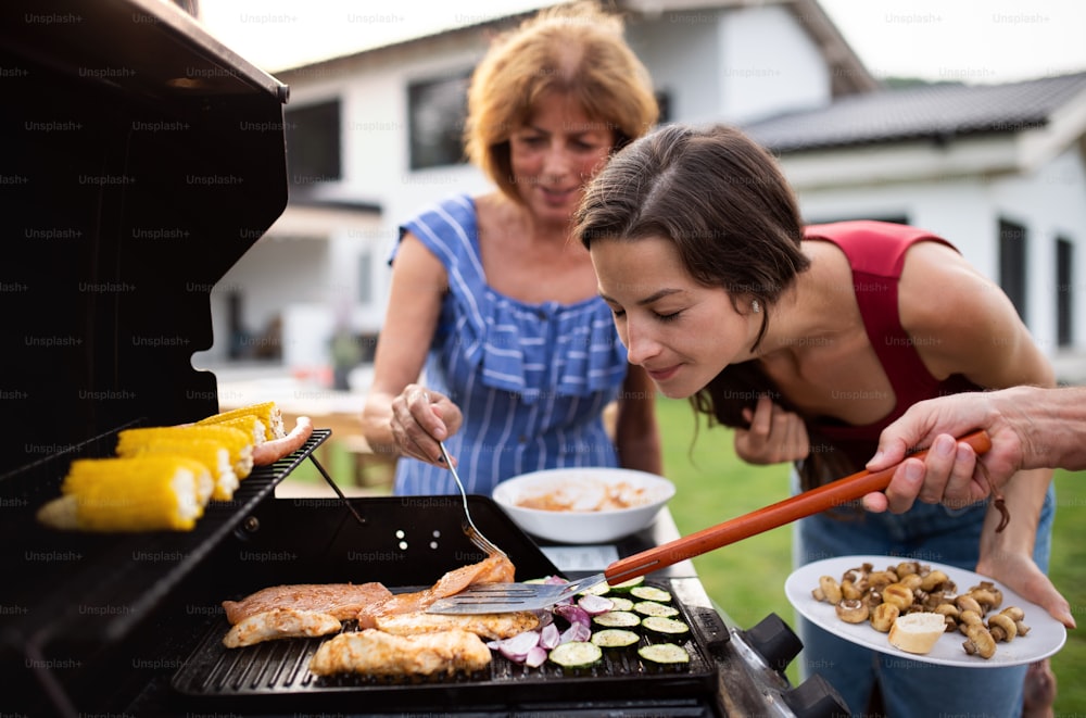 Porträt einer Mehrgenerationenfamilie im Freien beim Grillen, Grillen und Reden.