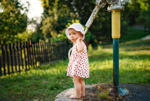 Una bambina in piedi all'aperto in giardino in estate. Copia spazio.