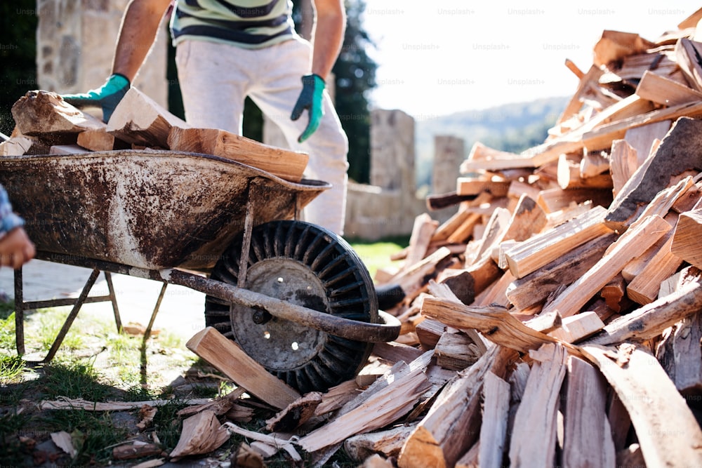 Midsection of unrecognizable man outdoors in summer, working with firewood.