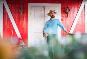 Um retrato de um agricultor maduro com um chapéu ao ar livre em frente à fazenda da família.