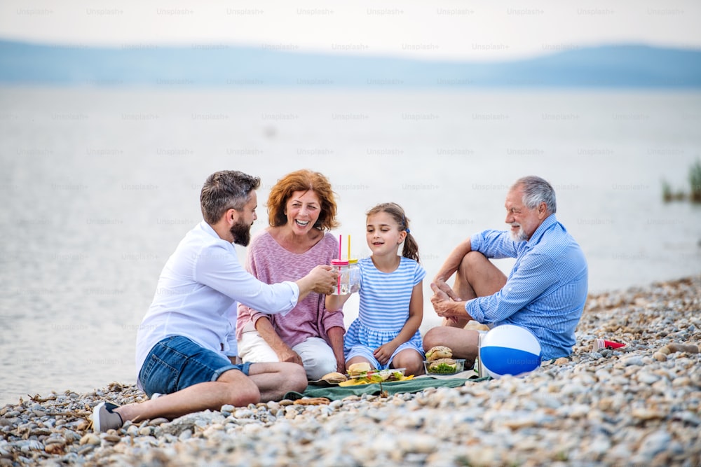 Eine Mehrgenerationenfamilie, die Urlaub am See macht und ein Picknick macht.
