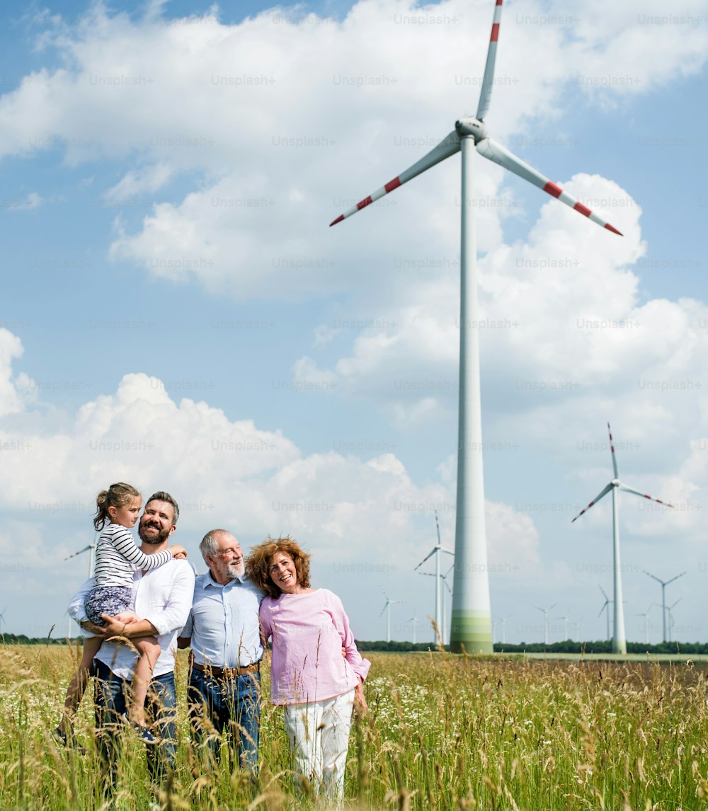 A front view of multigeneration family standing on field on wind farm.