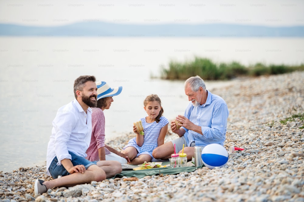 Uma família multigeração em férias à beira do lago, fazendo piquenique.