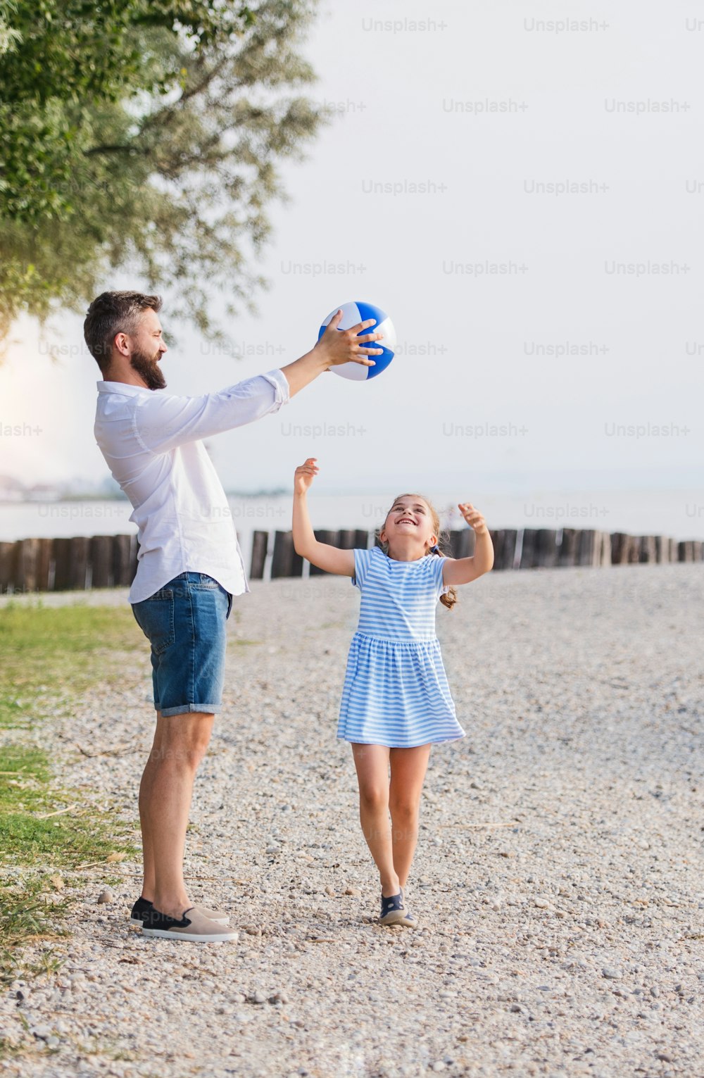 A mature father and small daughter on a holiday playing by the lake or sea.