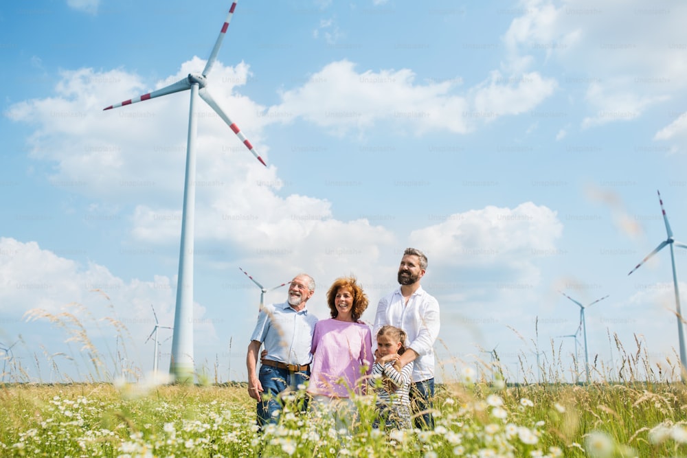 Eine Frontansicht einer Mehrgenerationenfamilie, die auf dem Feld eines Windparks steht.