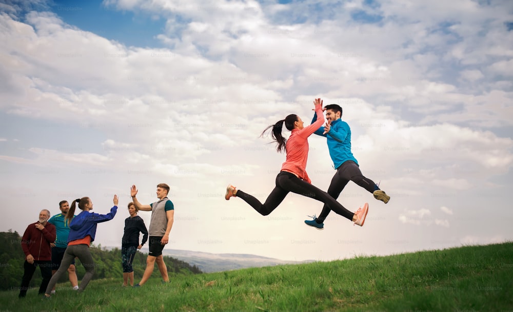 A large group of fit and active people jumping after doing exercise in nature.