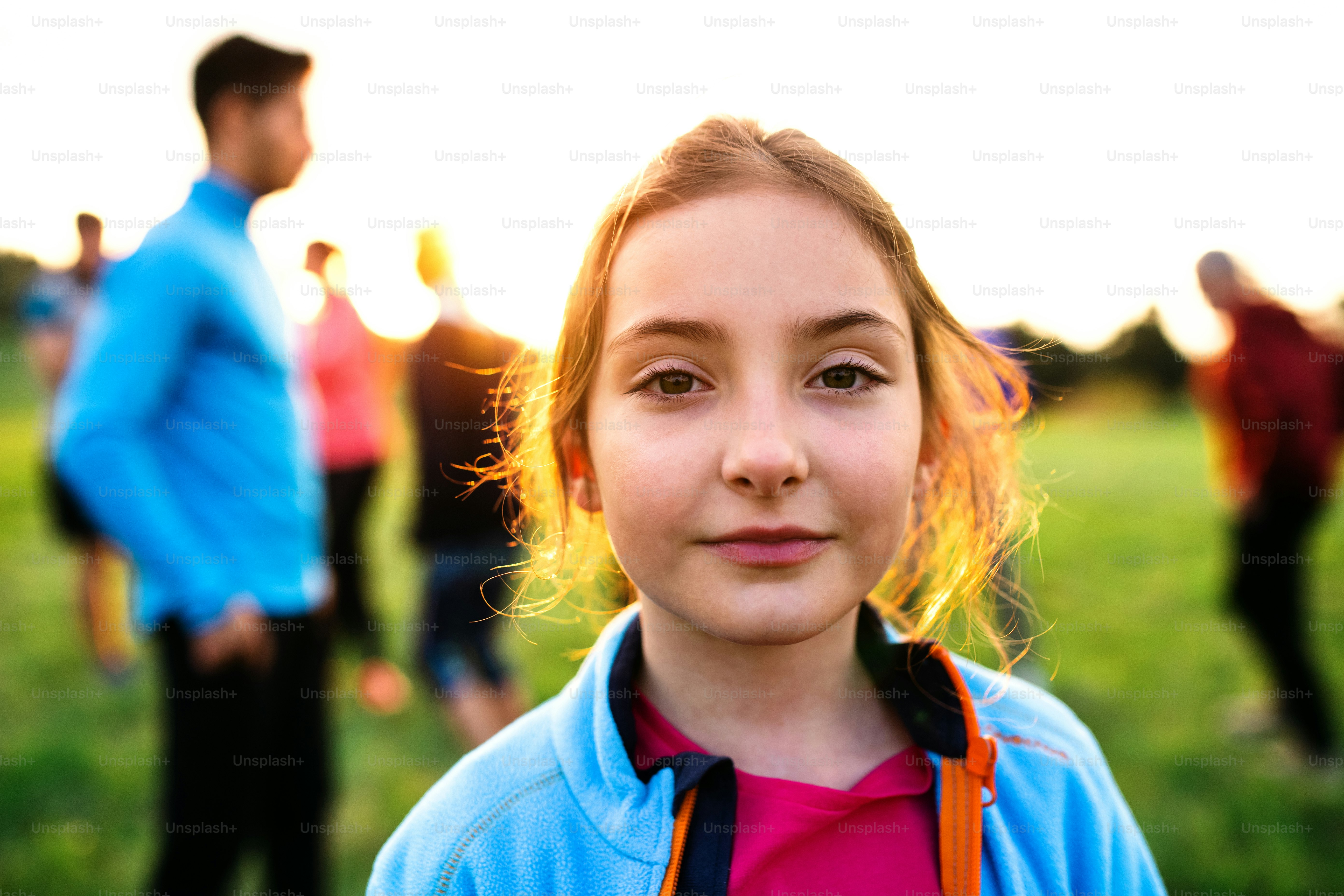 A portrait of small girl with large group of people doing exercise in nature, resting.