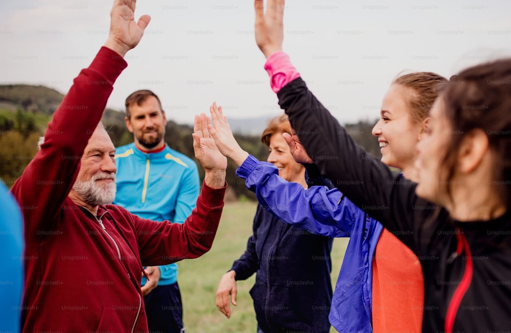 A large group of fit and active people resting after doing exercise in nature.