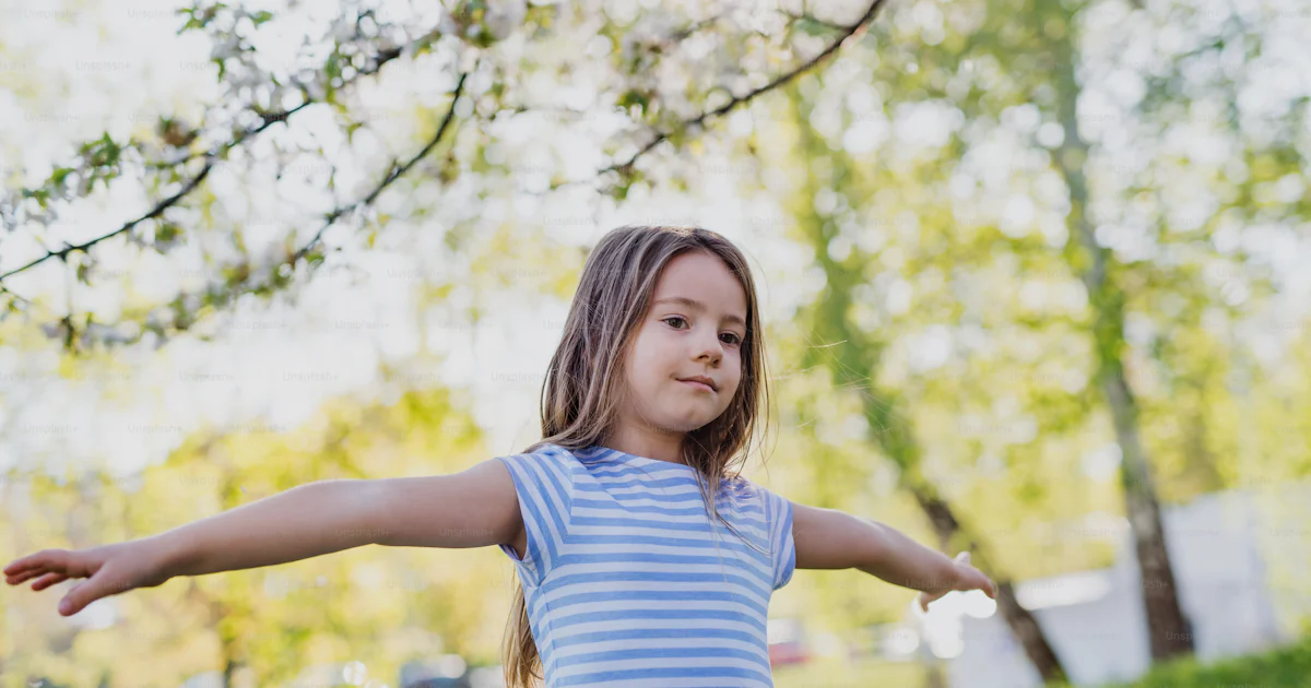 Playing Outside In Spring A front view of cheerful small girl playing outside in spring nature ...