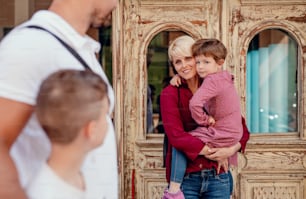 A midsection of young family with two small children walking outdoors in town.