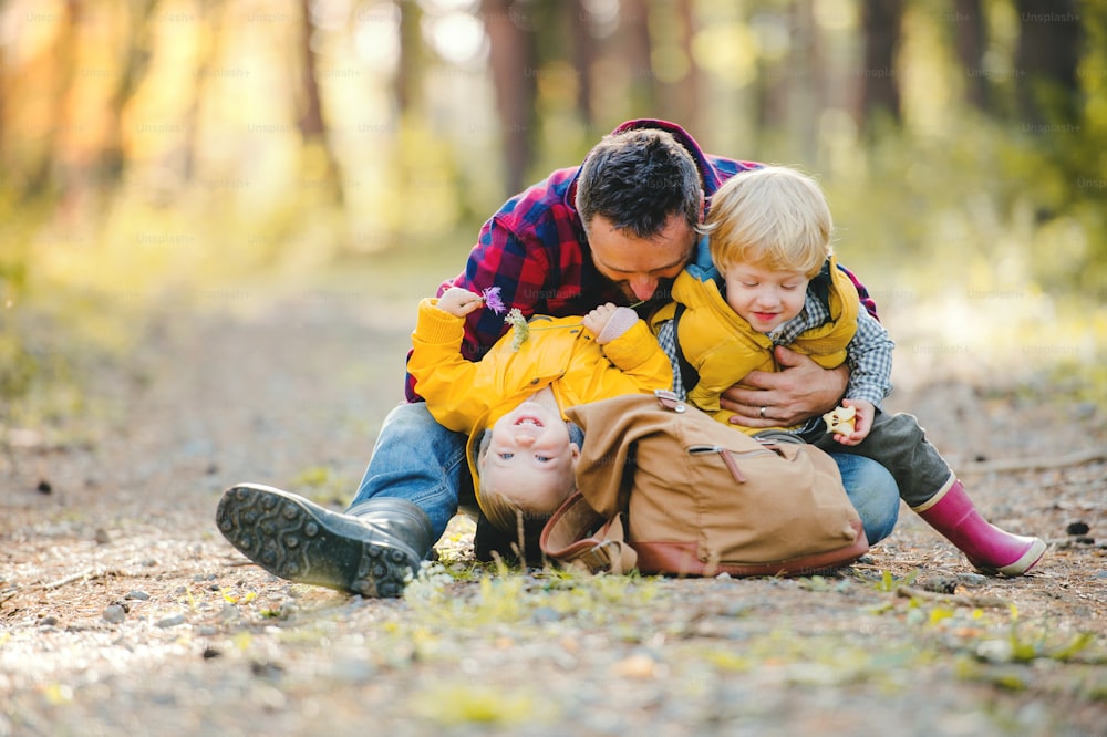 秋の森でバックパックと幼児の息子を持つ成熟した父親が休んでいます。