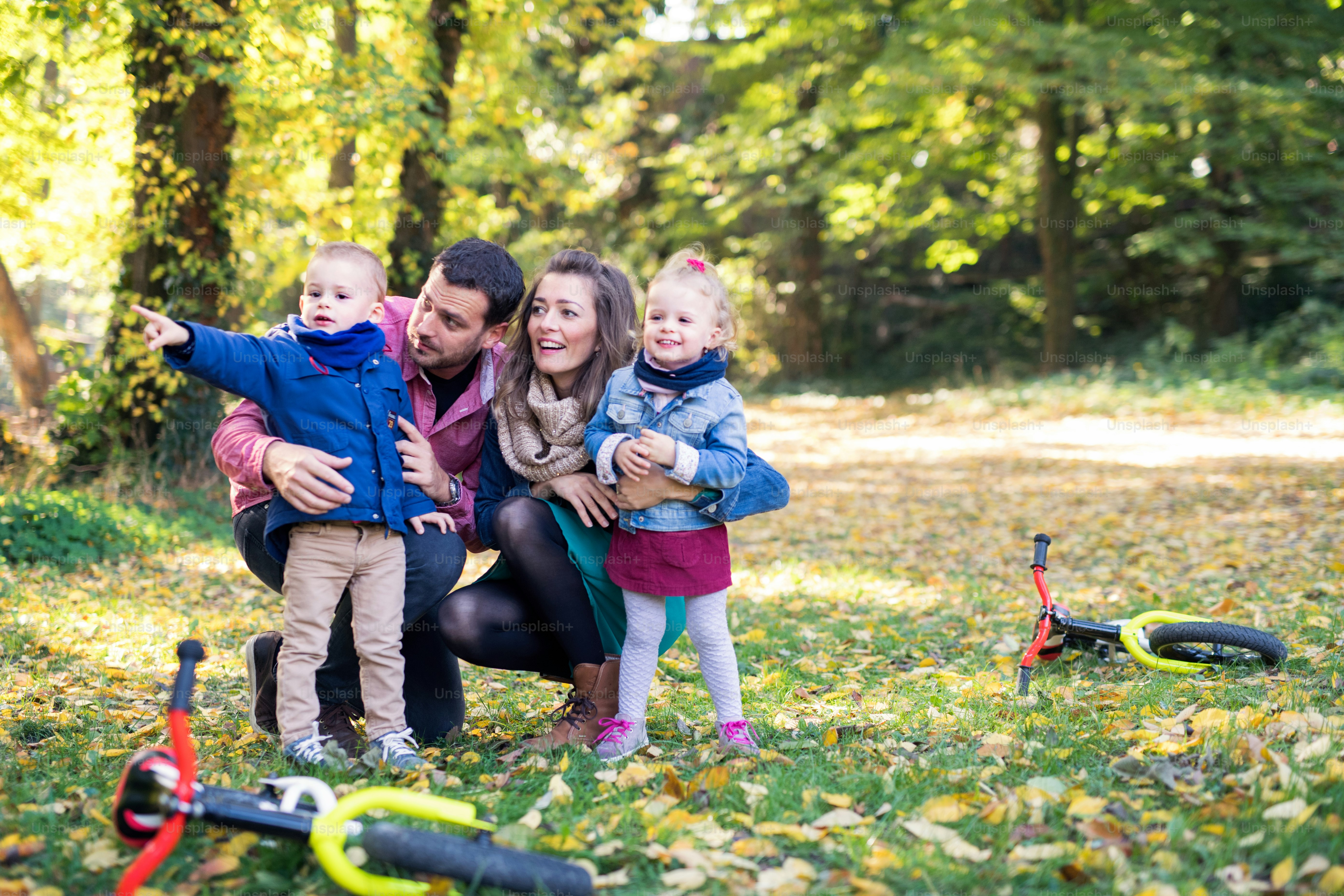 A portrait of beautiful young family with small twins on a walk in ...