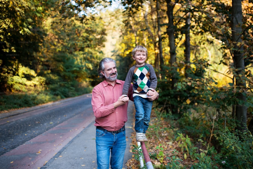 Mature father with small son on a walk in nature, walking on metal railing.