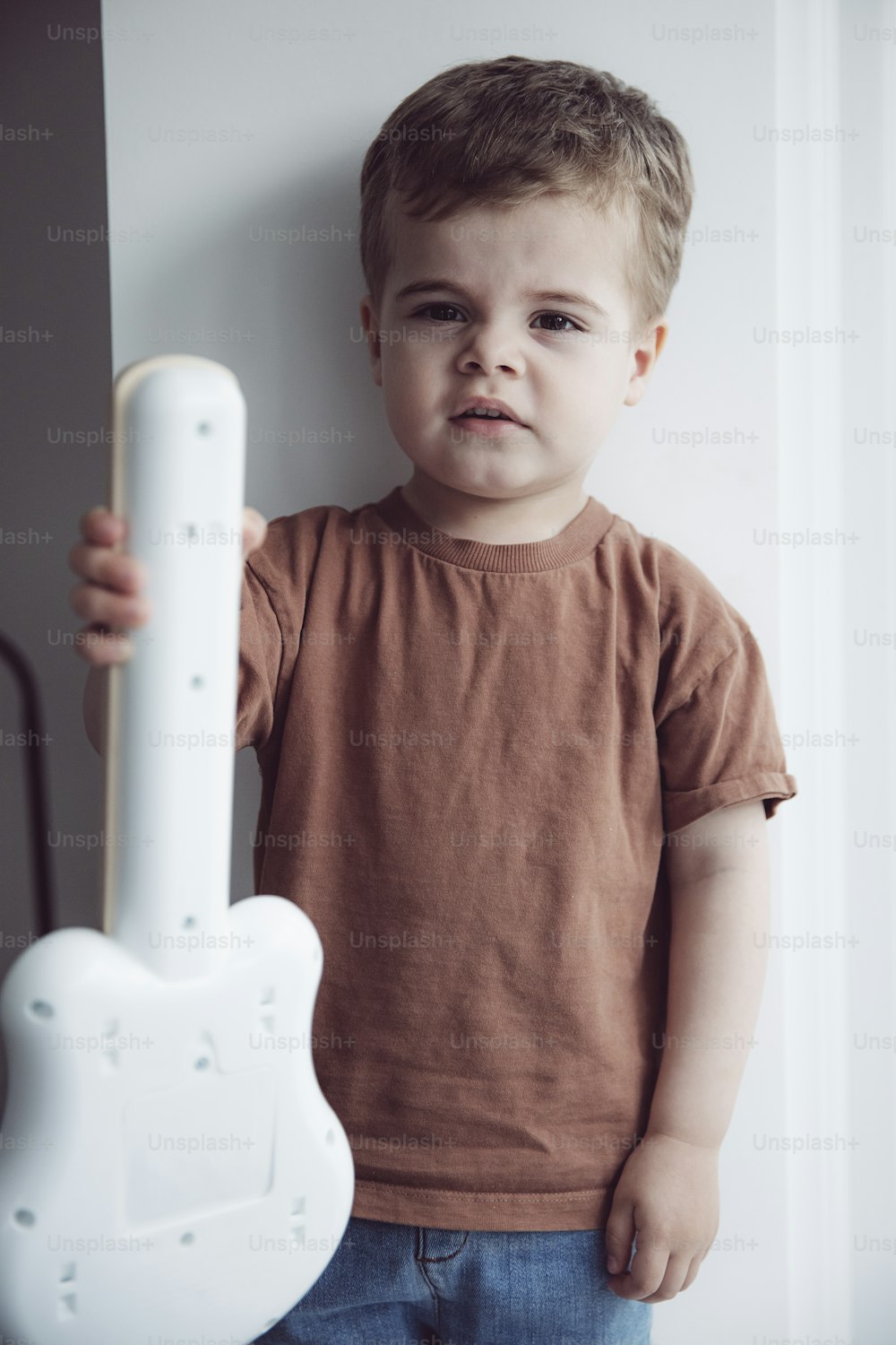 a young boy holding a white guitar shaped object
