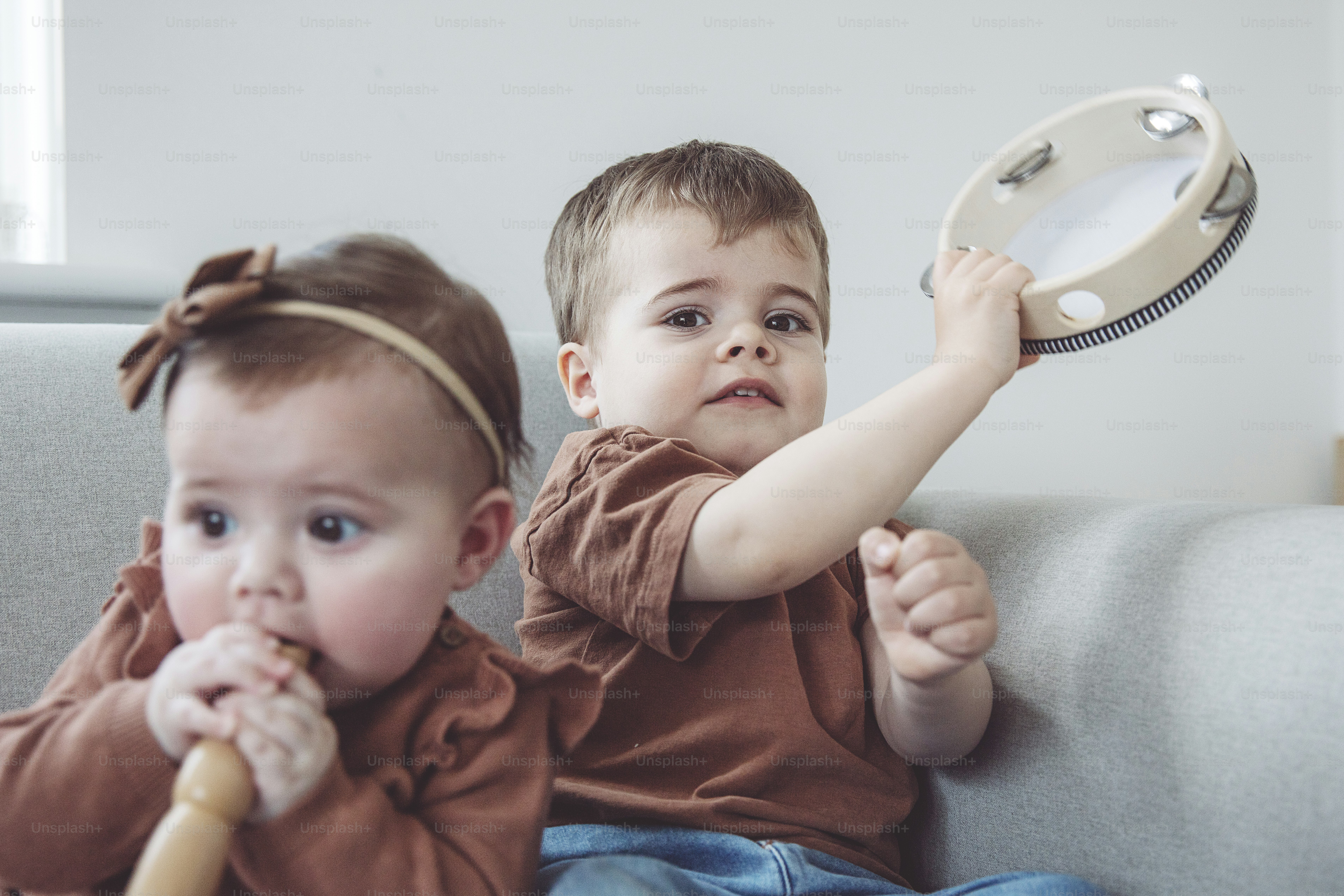 deux petits enfants assis sur un canapé avec un jouet