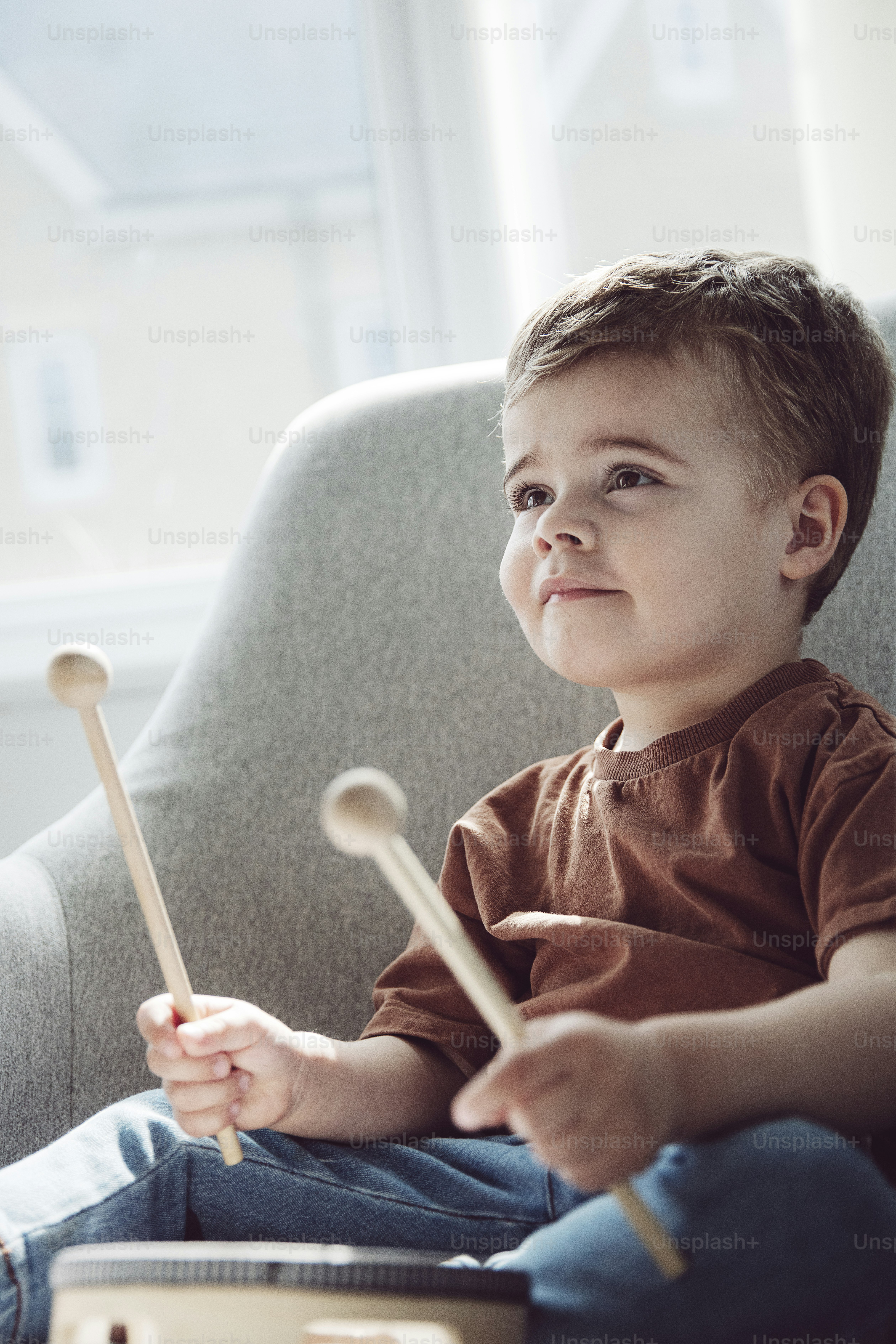Un petit garçon assis sur une chaise avec une batterie