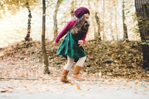 秋の自然の中で森の中を走る幸せな小さな幼児の女の子のポートレート。