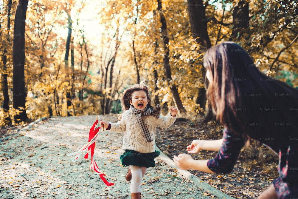 가을 자연에서 숲 속을 달리는 어린 딸을 안고 있는 젊은 어머니의 초상화.