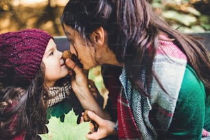Eine junge Mutter mit einer kleinen Tochter, die sich mit Nüssen im Wald in der Herbstnatur amüsiert.