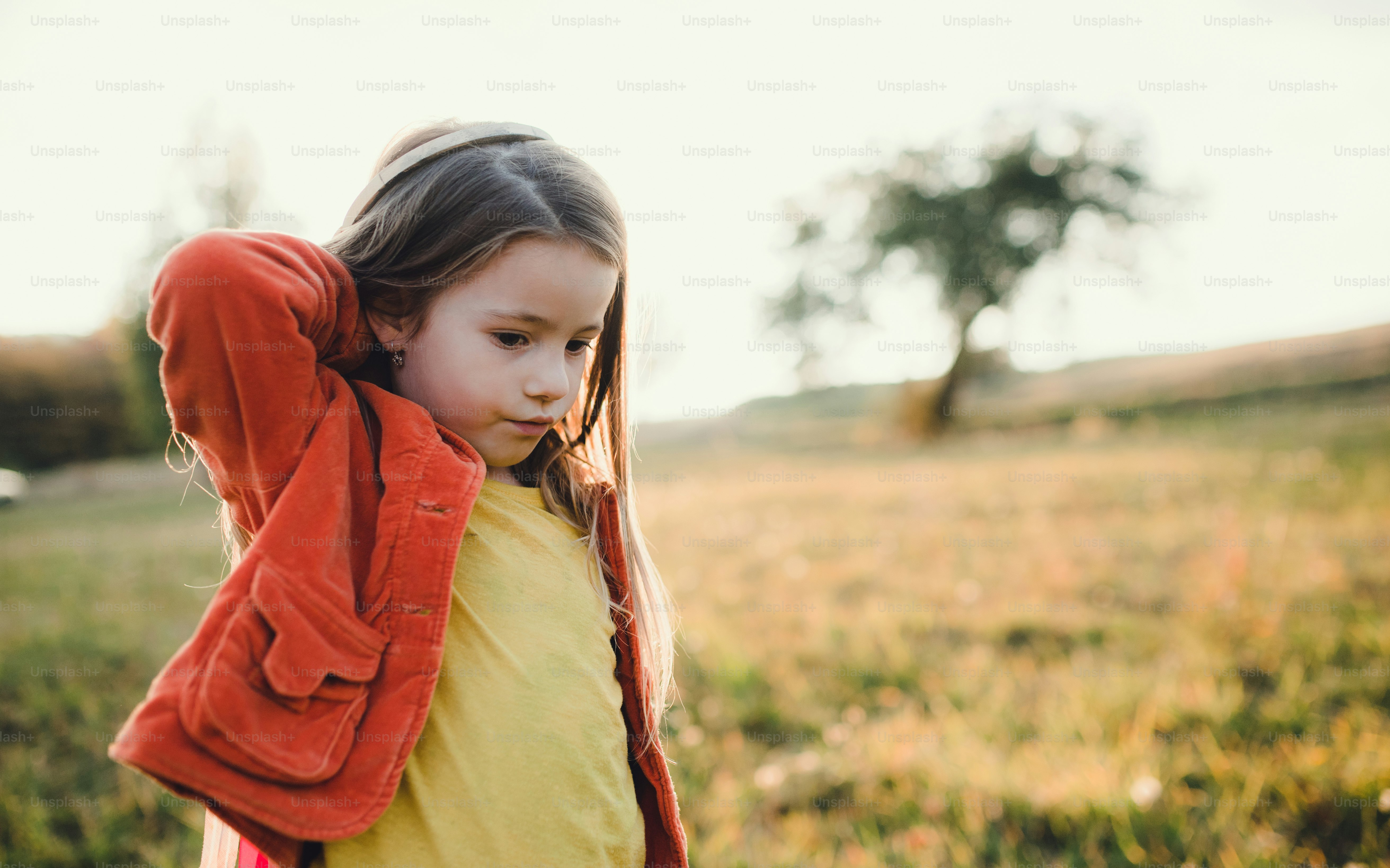 A happy small girl standing in autumn nature, pointing finger at ...